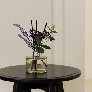 a glass vase with flowers and sticks on a table