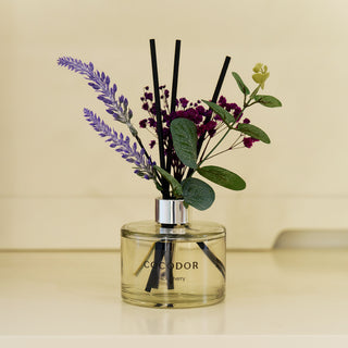 a glass bottle with flowers and sticks in it
