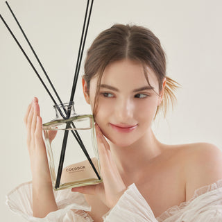 a woman holding a bottle of fragrance