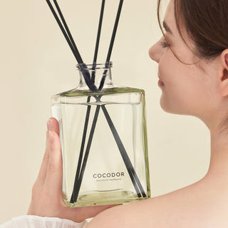 a woman holding a bottle of reed diffuser
