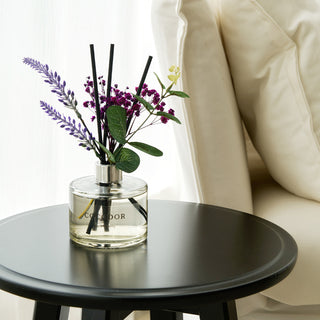 a small round table with a vase of flowers and sticks