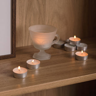 a teacup and candles on a shelf