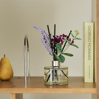 a vase with flowers and a pear on a shelf