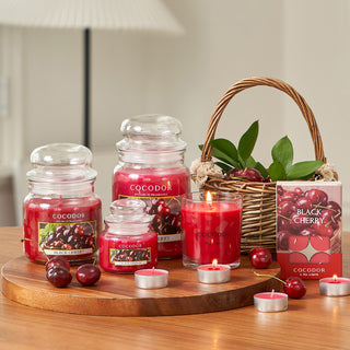a group of candles and a basket of cherries