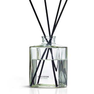 a glass bottle with black sticks in it