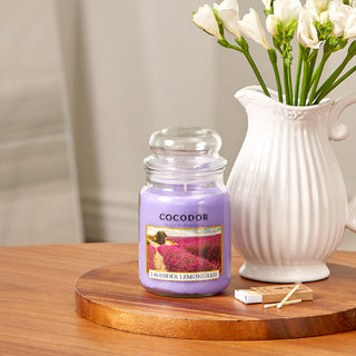 a candle and a vase of flowers on a wood surface