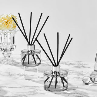 a group of glass bottles with black sticks and a flower in a vase