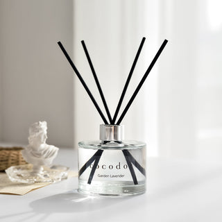 a glass bottle with black sticks in it